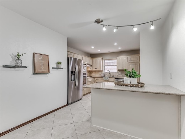 kitchen with appliances with stainless steel finishes, tasteful backsplash, sink, light tile patterned floors, and kitchen peninsula