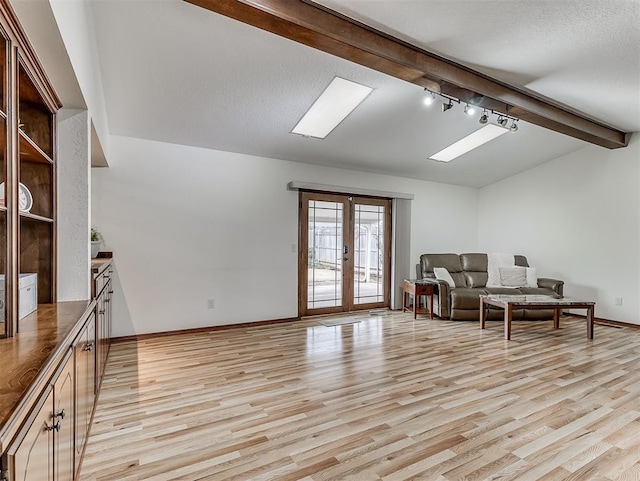 living room featuring vaulted ceiling with beams, light hardwood / wood-style flooring, a textured ceiling, and french doors