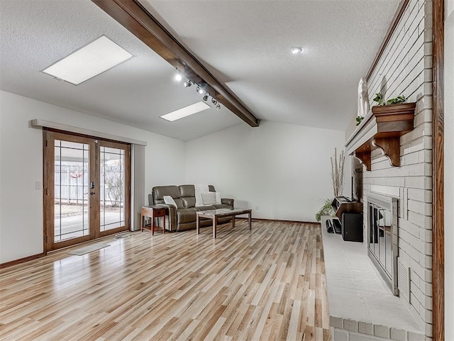 living area with lofted ceiling with beams, a textured ceiling, and light wood-type flooring