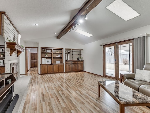 unfurnished living room with vaulted ceiling with beams, a textured ceiling, light hardwood / wood-style floors, and french doors