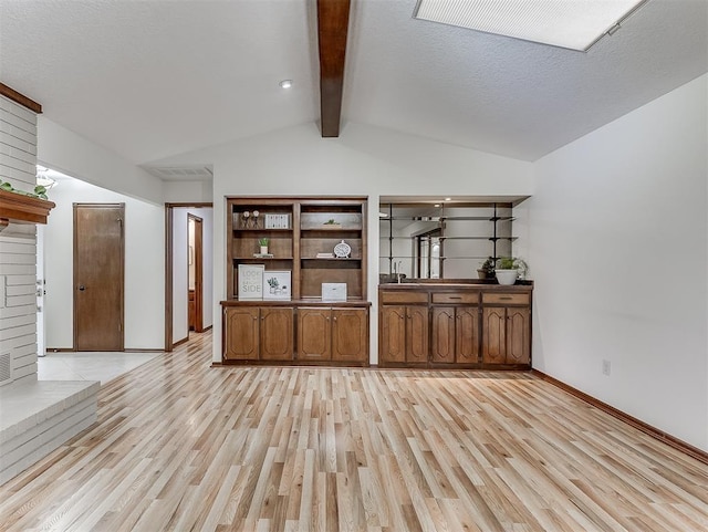 interior space with lofted ceiling with beams, light hardwood / wood-style flooring, and a textured ceiling