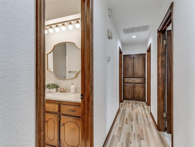 hall with sink and light wood-type flooring