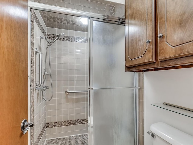 bathroom featuring a shower with shower door and toilet