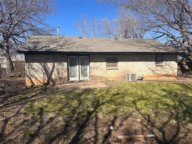 back of house featuring brick siding, cooling unit, a yard, and roof with shingles