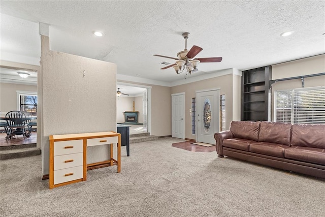 living room featuring ceiling fan, plenty of natural light, carpet floors, and a textured ceiling