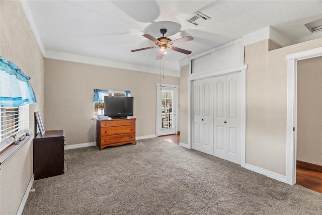 unfurnished bedroom featuring a textured ceiling, carpet floors, a closet, and ceiling fan