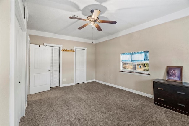 unfurnished bedroom with ceiling fan, multiple closets, and carpet