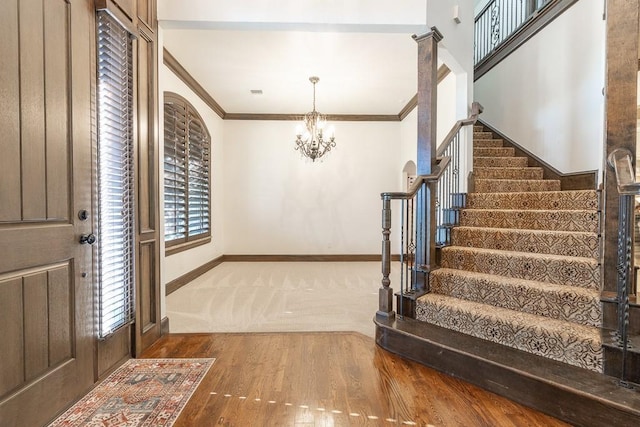 foyer featuring crown molding, a chandelier, and hardwood / wood-style flooring