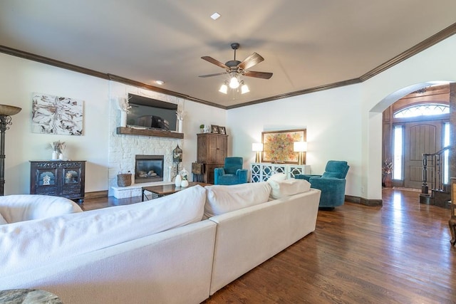 living room with crown molding, a fireplace, dark hardwood / wood-style floors, and ceiling fan