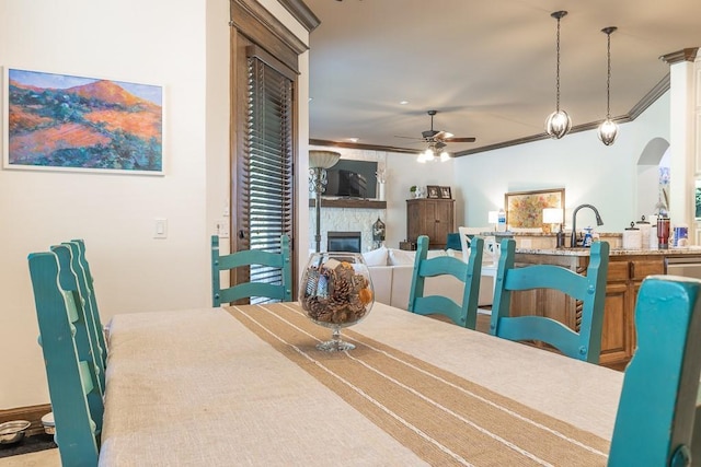 dining space with ceiling fan, ornamental molding, and sink