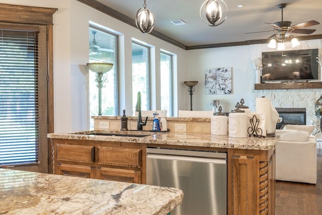 kitchen with a fireplace, sink, ornamental molding, stainless steel dishwasher, and light stone countertops