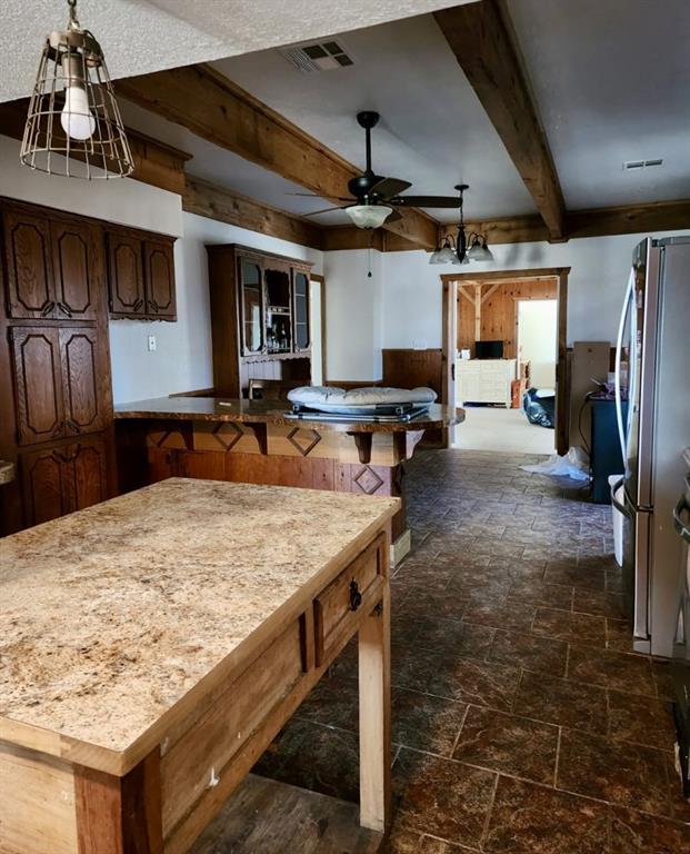 kitchen with beamed ceiling, stainless steel fridge, ceiling fan, and dark brown cabinetry