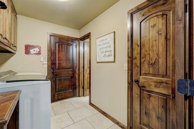 clothes washing area with cabinets, washing machine and dryer, and light tile patterned floors