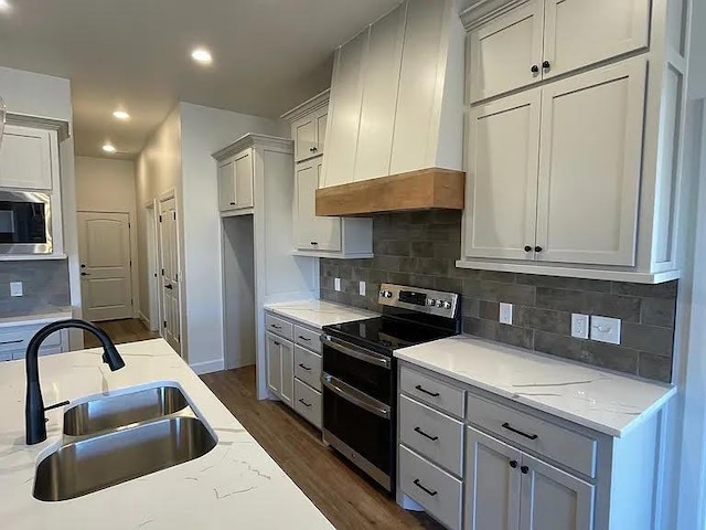 kitchen featuring sink, dark wood-type flooring, stainless steel appliances, light stone countertops, and custom range hood