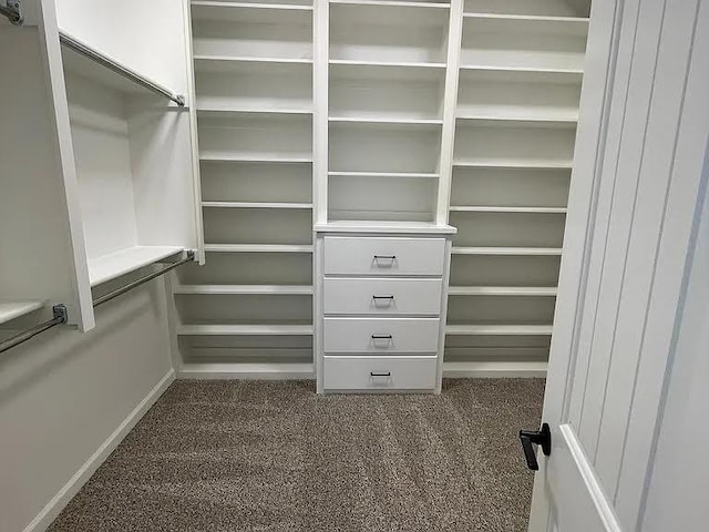 walk in closet with dark carpet