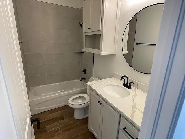 full bathroom featuring tiled shower / bath, hardwood / wood-style floors, vanity, and toilet