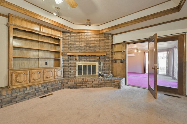 unfurnished living room featuring a fireplace, carpet flooring, ornamental molding, ceiling fan, and a wall unit AC