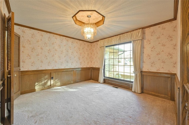 spare room with crown molding, light colored carpet, an inviting chandelier, and a textured ceiling