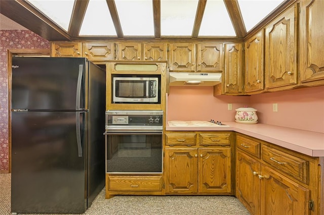 kitchen with black refrigerator, stovetop, and oven