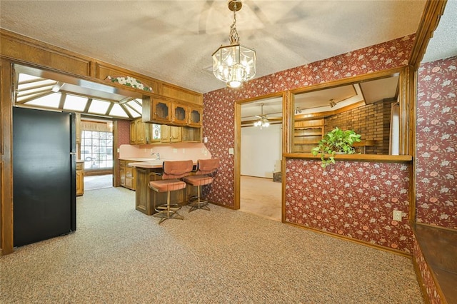 kitchen with hanging light fixtures, a kitchen breakfast bar, a textured ceiling, light colored carpet, and kitchen peninsula