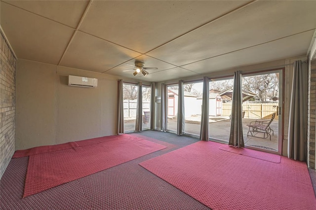 unfurnished sunroom with ceiling fan and a wall mounted air conditioner