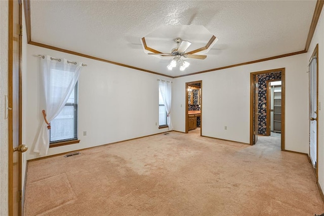 carpeted spare room featuring ceiling fan, crown molding, and a textured ceiling