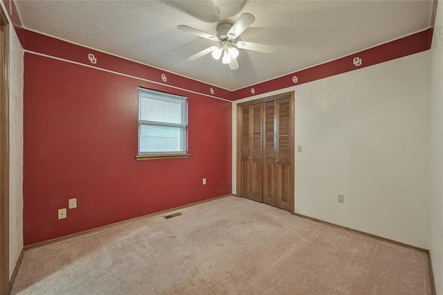 unfurnished bedroom featuring light carpet, ceiling fan, a closet, and a textured ceiling