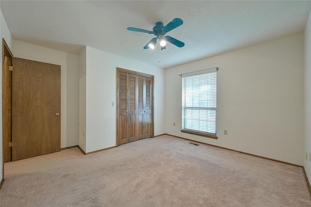 unfurnished bedroom with light colored carpet, ceiling fan, and a closet