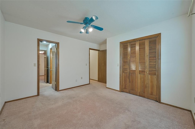 unfurnished bedroom with light colored carpet, a closet, and ceiling fan