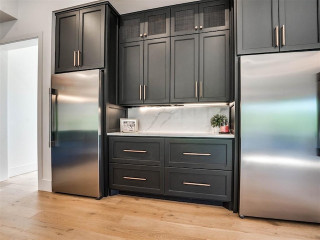 kitchen featuring backsplash, light hardwood / wood-style flooring, and stainless steel refrigerator