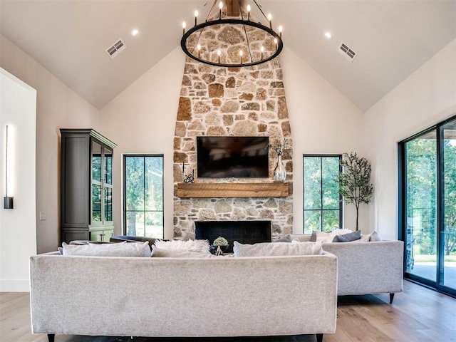 living room featuring a stone fireplace, a wealth of natural light, and light hardwood / wood-style floors