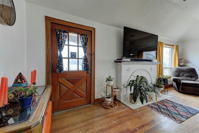 entrance foyer with a healthy amount of sunlight, hardwood / wood-style floors, and a brick fireplace