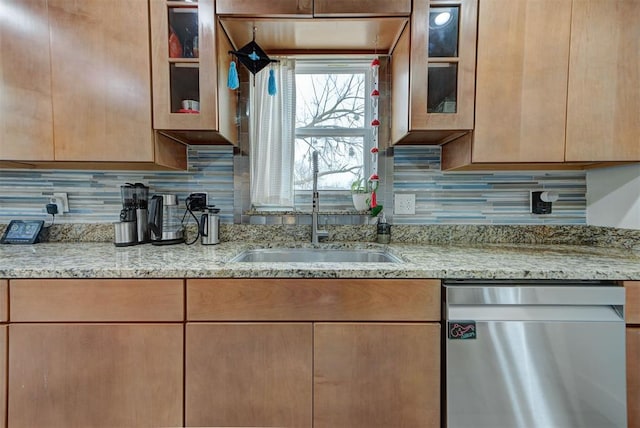 kitchen with stainless steel dishwasher, light stone countertops, sink, and decorative backsplash