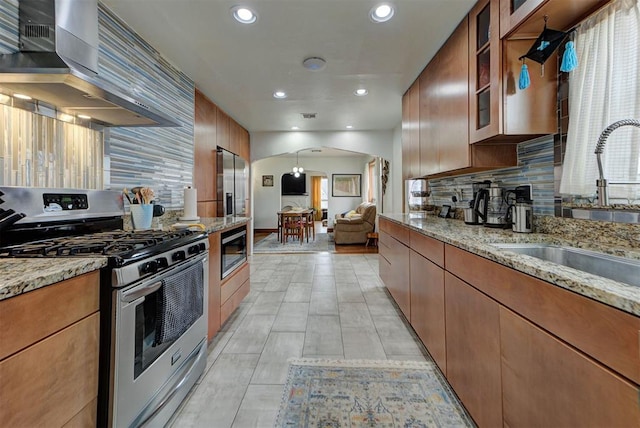 kitchen featuring appliances with stainless steel finishes, tasteful backsplash, sink, light stone countertops, and wall chimney exhaust hood