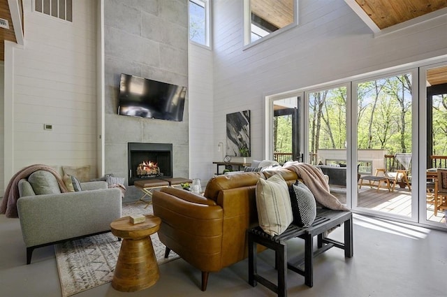 living room featuring a towering ceiling, concrete flooring, and a tile fireplace