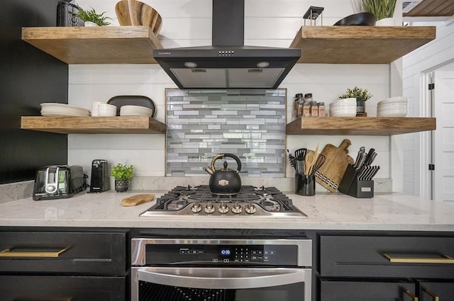 kitchen featuring stainless steel appliances, decorative backsplash, light stone counters, and range hood