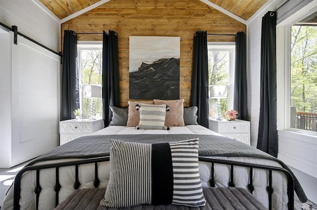 bedroom with lofted ceiling, wood ceiling, wooden walls, and a barn door