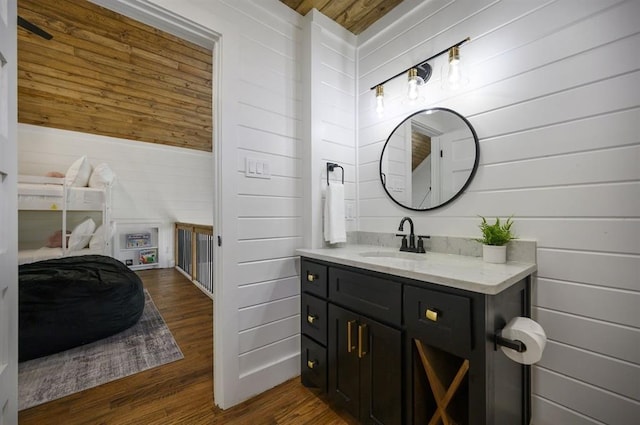 bathroom featuring vanity, wooden walls, and hardwood / wood-style floors