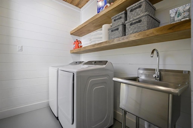 clothes washing area featuring independent washer and dryer and wood walls