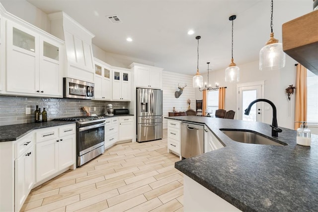 kitchen with sink, hanging light fixtures, appliances with stainless steel finishes, an island with sink, and white cabinets