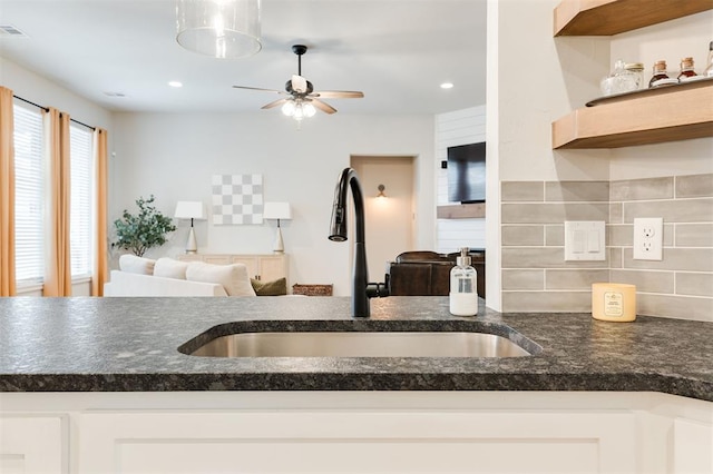 kitchen with sink, backsplash, white cabinets, and ceiling fan