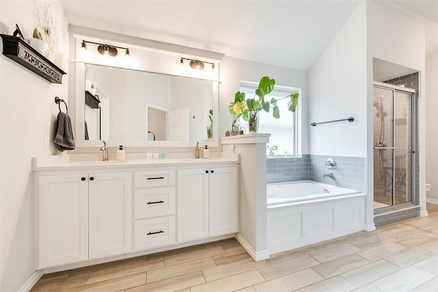 bathroom with lofted ceiling, vanity, and separate shower and tub