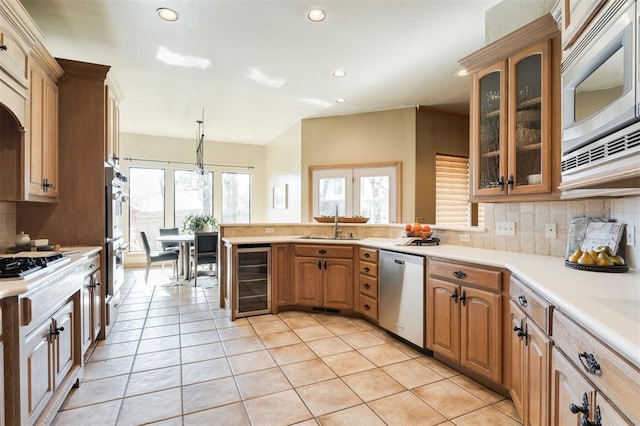 kitchen with sink, decorative light fixtures, stainless steel appliances, beverage cooler, and backsplash