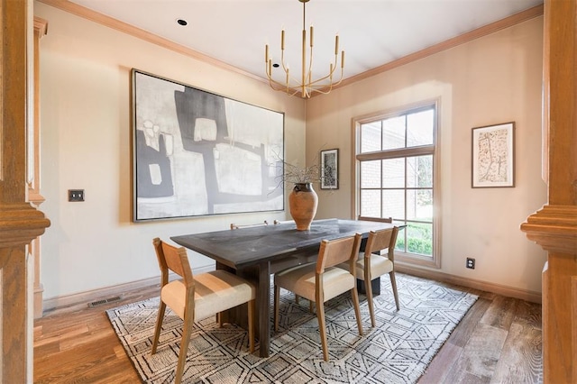 dining space with ornamental molding, an inviting chandelier, and light hardwood / wood-style flooring