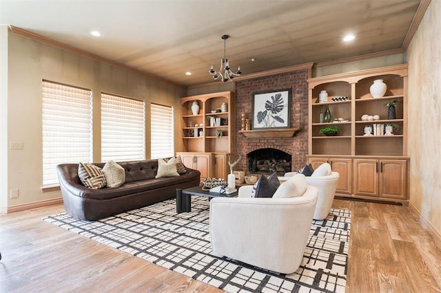 living room with ornamental molding, a fireplace, light hardwood / wood-style flooring, and a notable chandelier