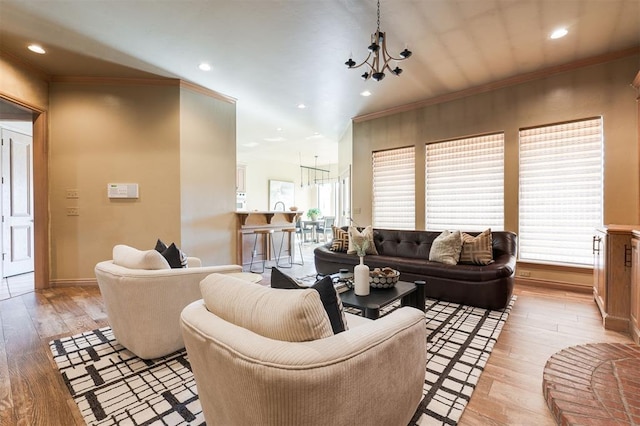 living room with ornamental molding, an inviting chandelier, and light hardwood / wood-style flooring