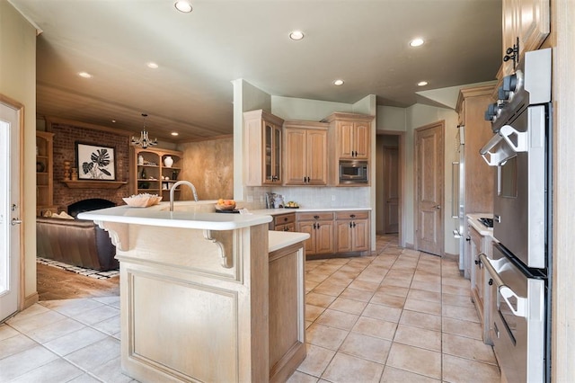 kitchen with light tile patterned floors, backsplash, stainless steel appliances, a kitchen bar, and kitchen peninsula