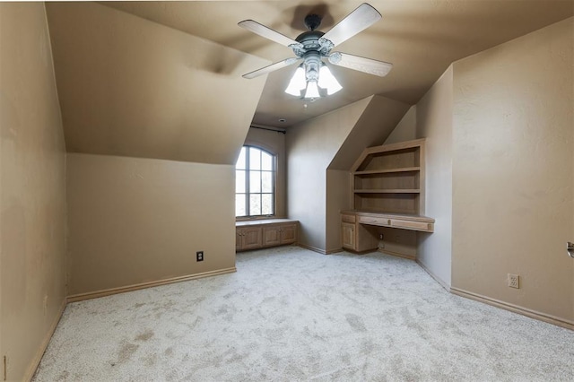 bonus room featuring light carpet, built in desk, lofted ceiling, and ceiling fan