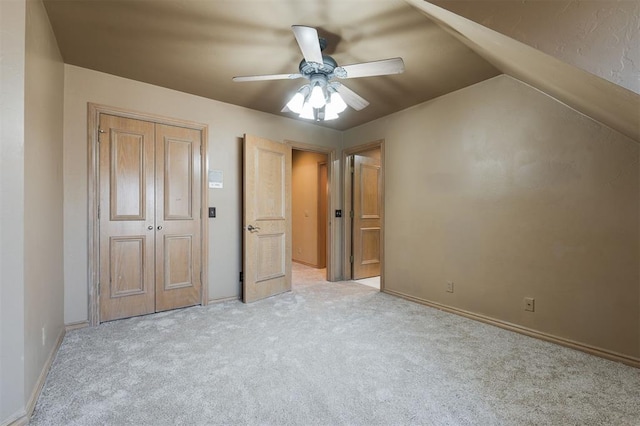 unfurnished bedroom with light carpet, vaulted ceiling, a closet, and ceiling fan