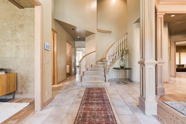 tiled foyer featuring a towering ceiling and ornate columns